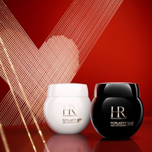 Photo produit de la Creme de Jour Re-Plasty Age Recovery et de la Creme de Nuit Re-Plasty Age Recovery d'Helena Rubinstein, respectivement dans un pot blanc brillant et un pot noir brillant. Les pots sont places cote a cote sur une surface rouge reflechissante, sur fond rouge profond orne d'un coeur en art lineaire dore.​