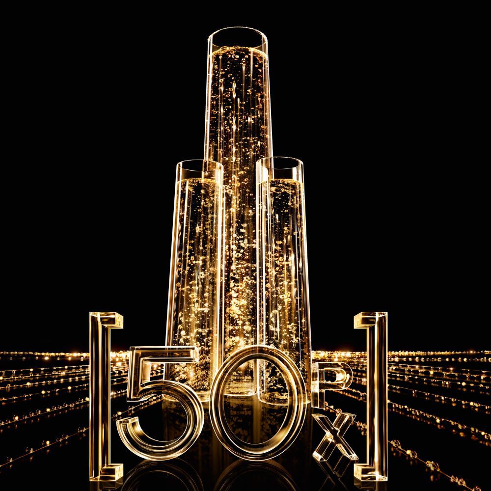Drie verticale glazen buizen gevuld met sprankelende gouden vloeistof, met de lichtgevende "50X" cijfers ervoor, op een zwarte achtergrond met gouden lichtsporen.