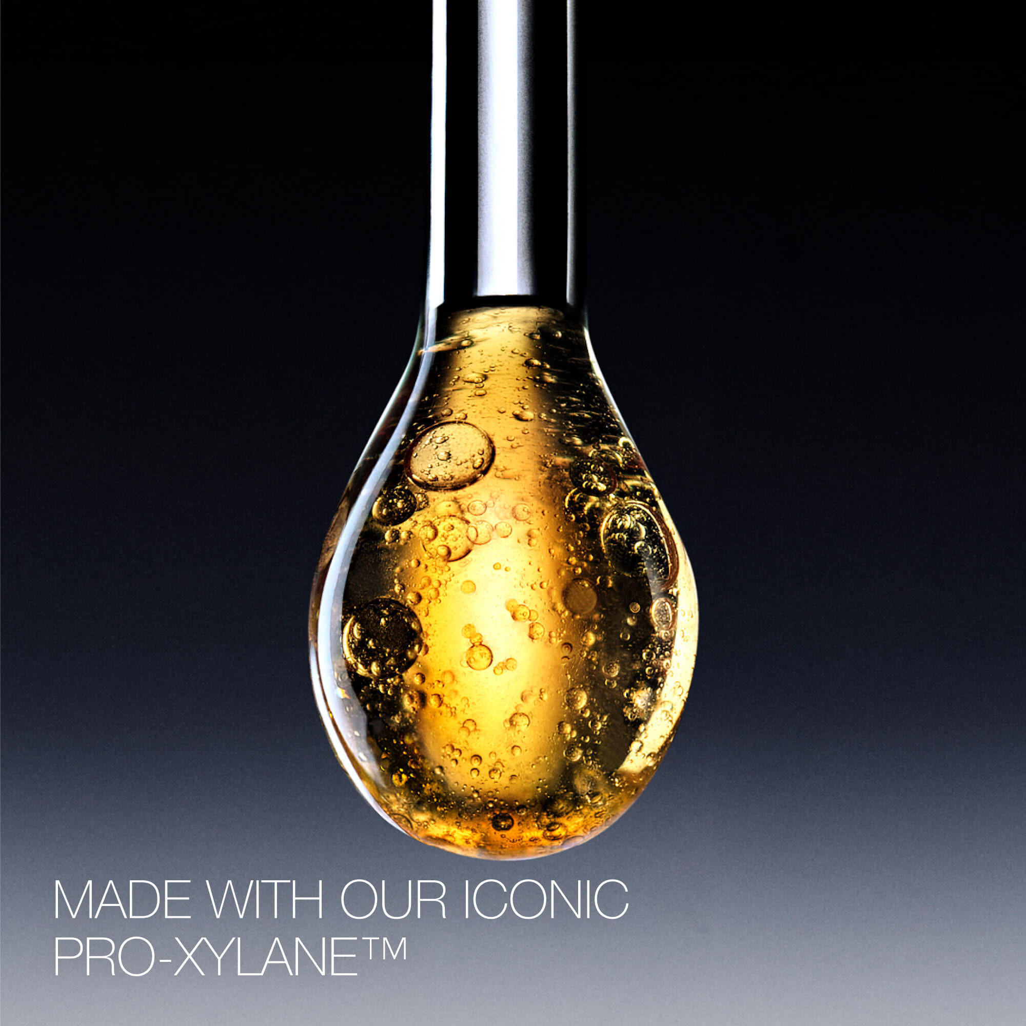 Gouden serumdruppel met Pro-Xylane™ ingredient, die de rijke, bruisende textuur en luxueuze essentie toont.